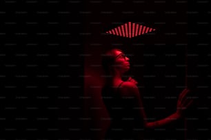 une femme debout dans une pièce sombre avec une lumière rouge sur la tête