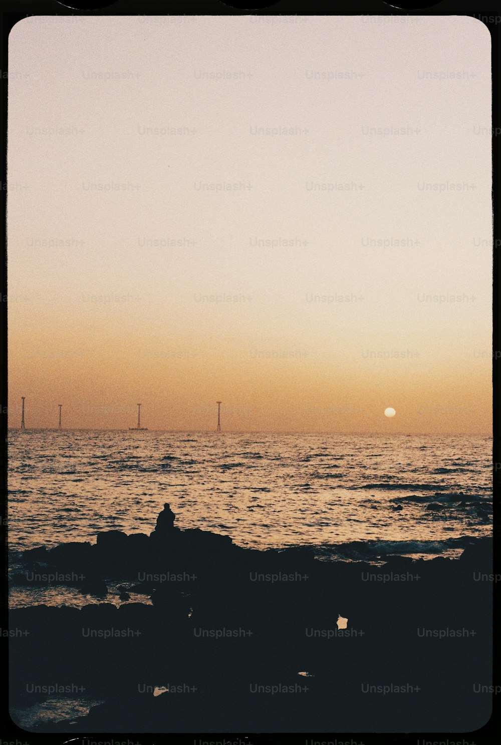 a person sitting on a rock watching the sunset