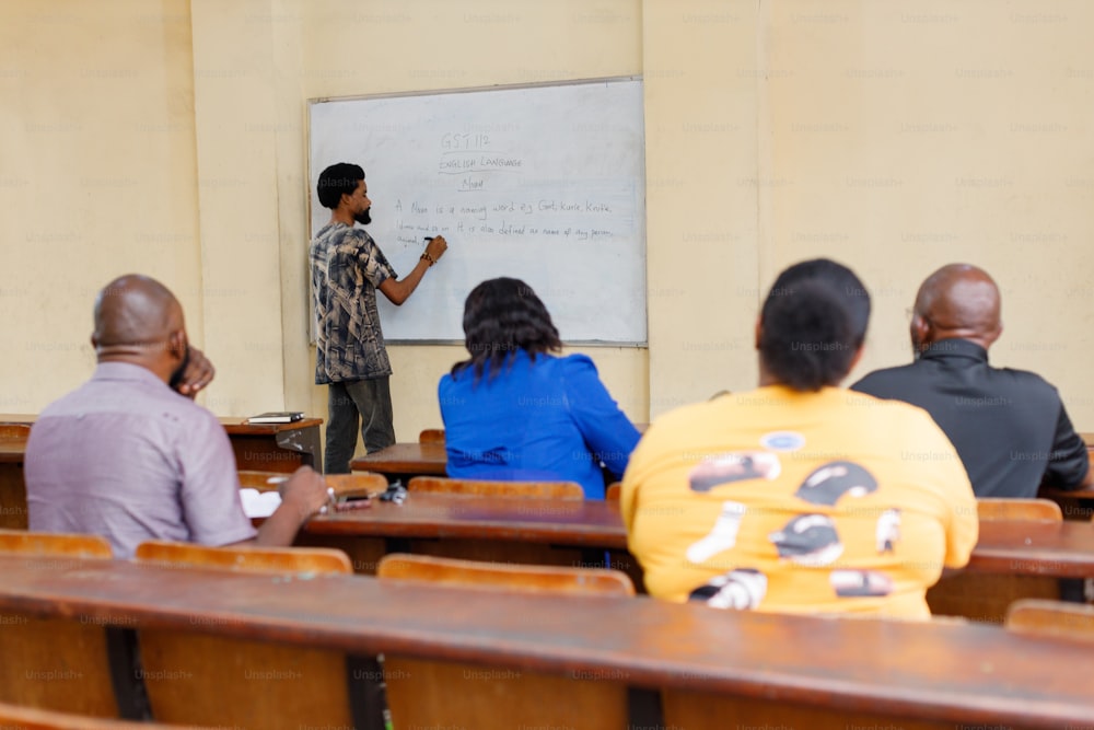 a man standing in front of a whiteboard in a classroom