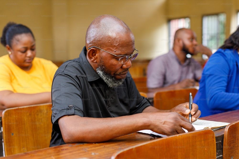 un homme assis à un bureau écrivant sur un morceau de papier