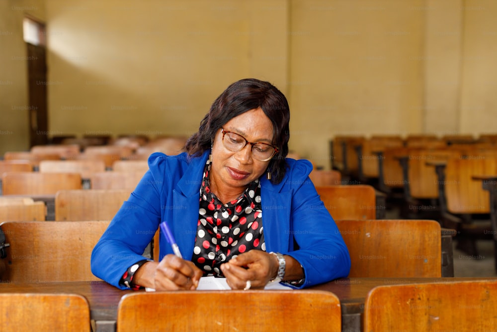 una mujer sentada en un escritorio escribiendo en un pedazo de papel