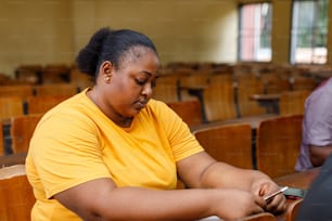una mujer con una camisa amarilla sentada en un aula
