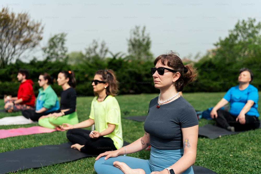 a group of people sitting on yoga mats in a park