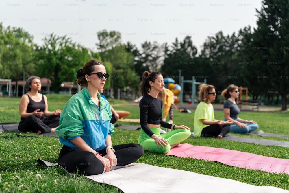 a group of people sitting in a park doing yoga