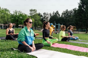 a group of people sitting in a park doing yoga
