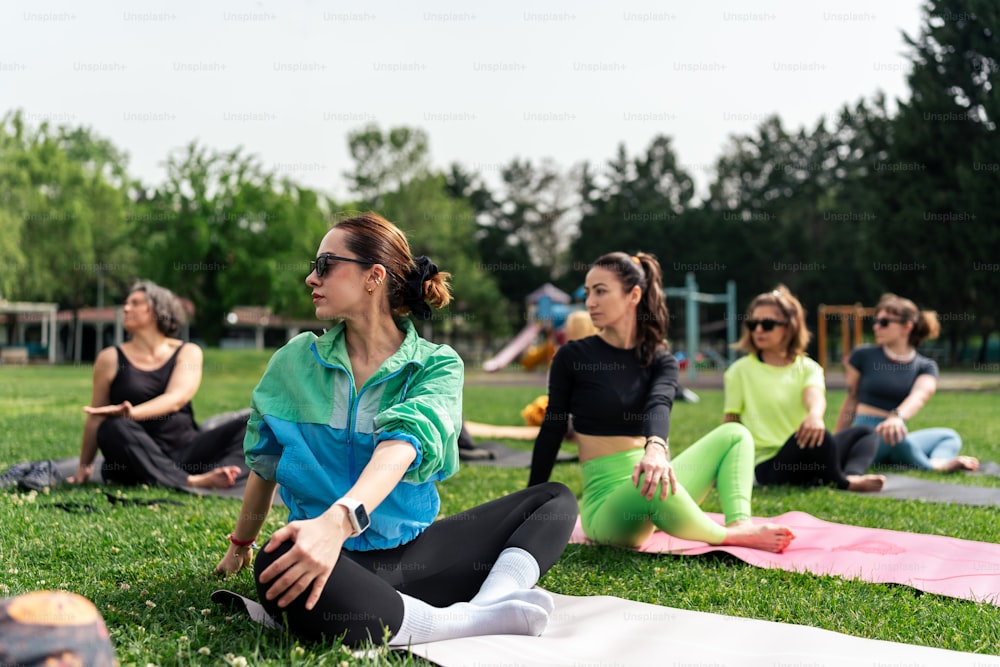 a group of women sitting on top of a lush green field