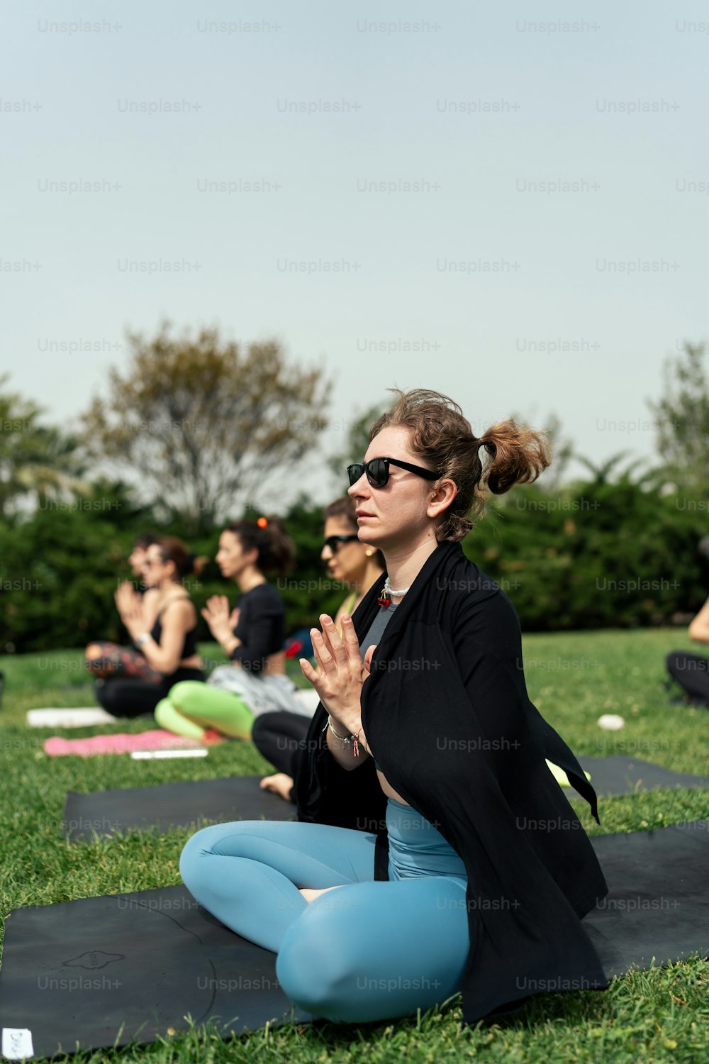 una mujer sentada en una esterilla de yoga en un parque