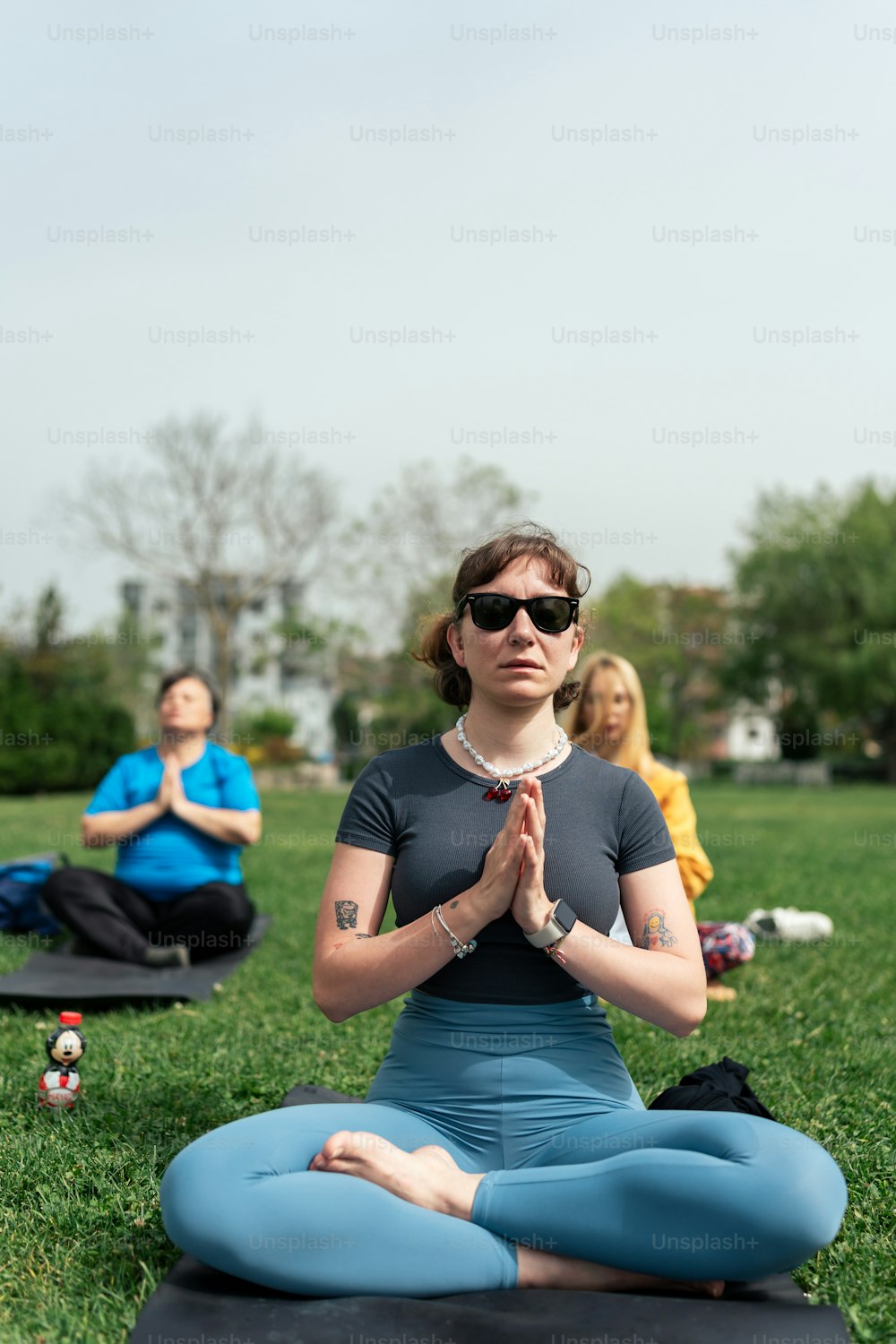 a group of people sitting in a field doing yoga