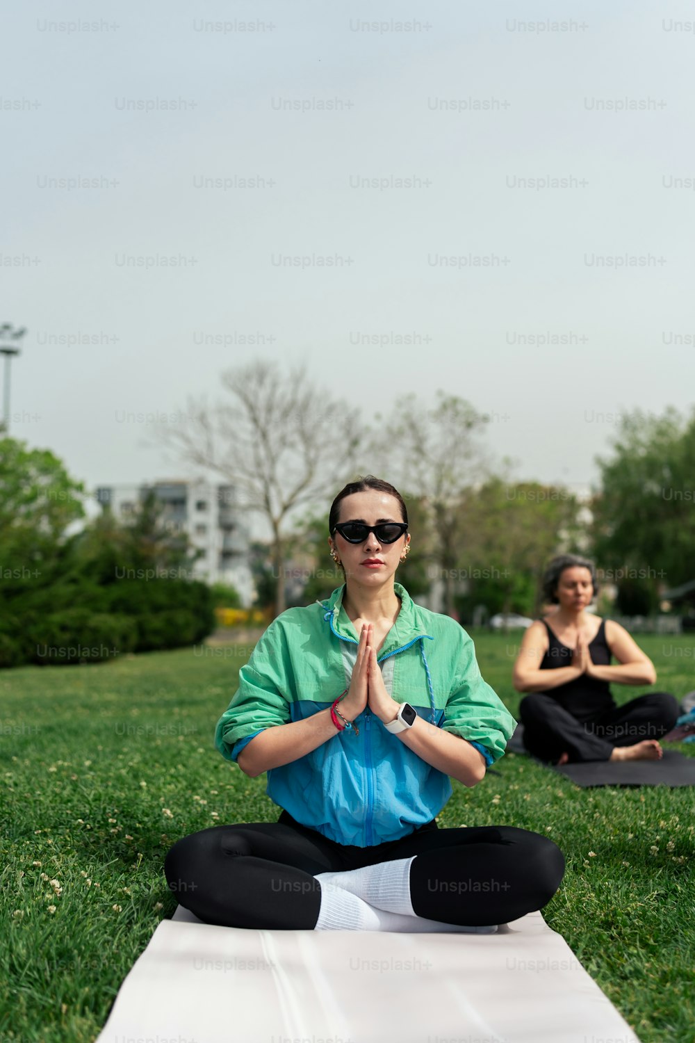 una mujer sentada en una posición de yoga en un parque