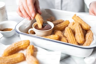 a person dipping sauce into a bowl of churros