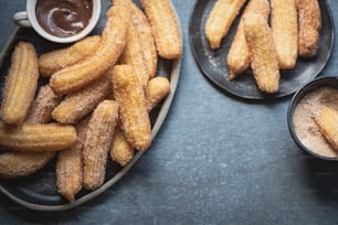 two plates of churros and dipping sauce on a table