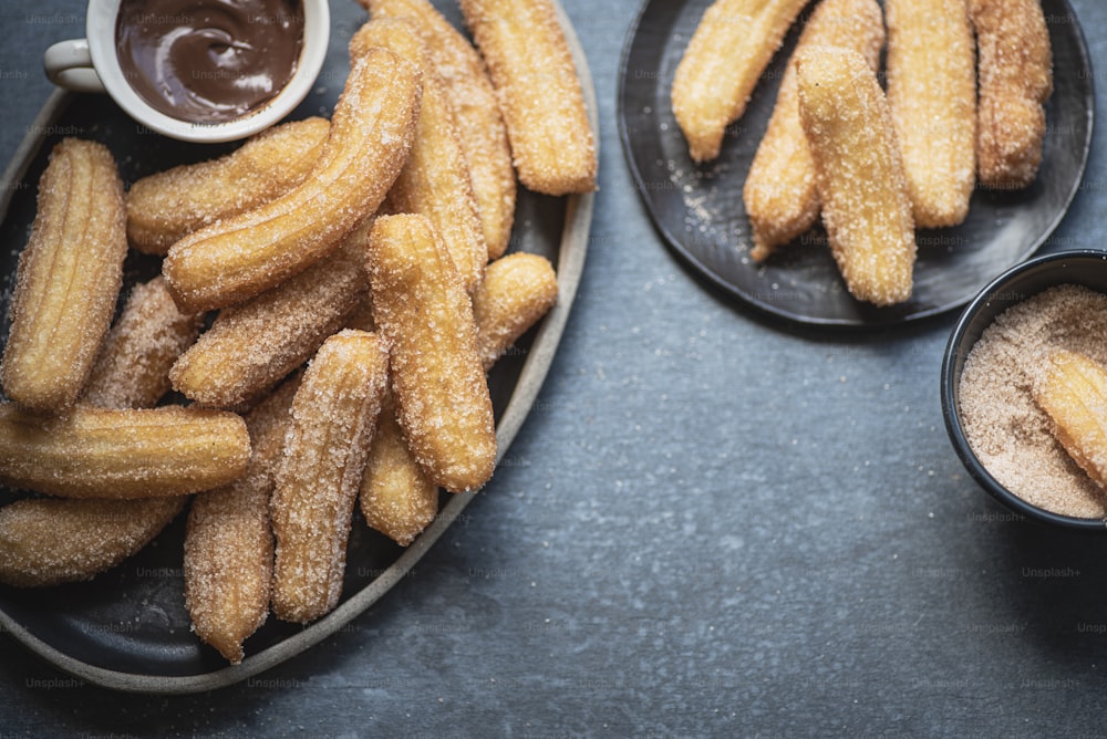 Dos platos de churros y salsa para mojar en una mesa