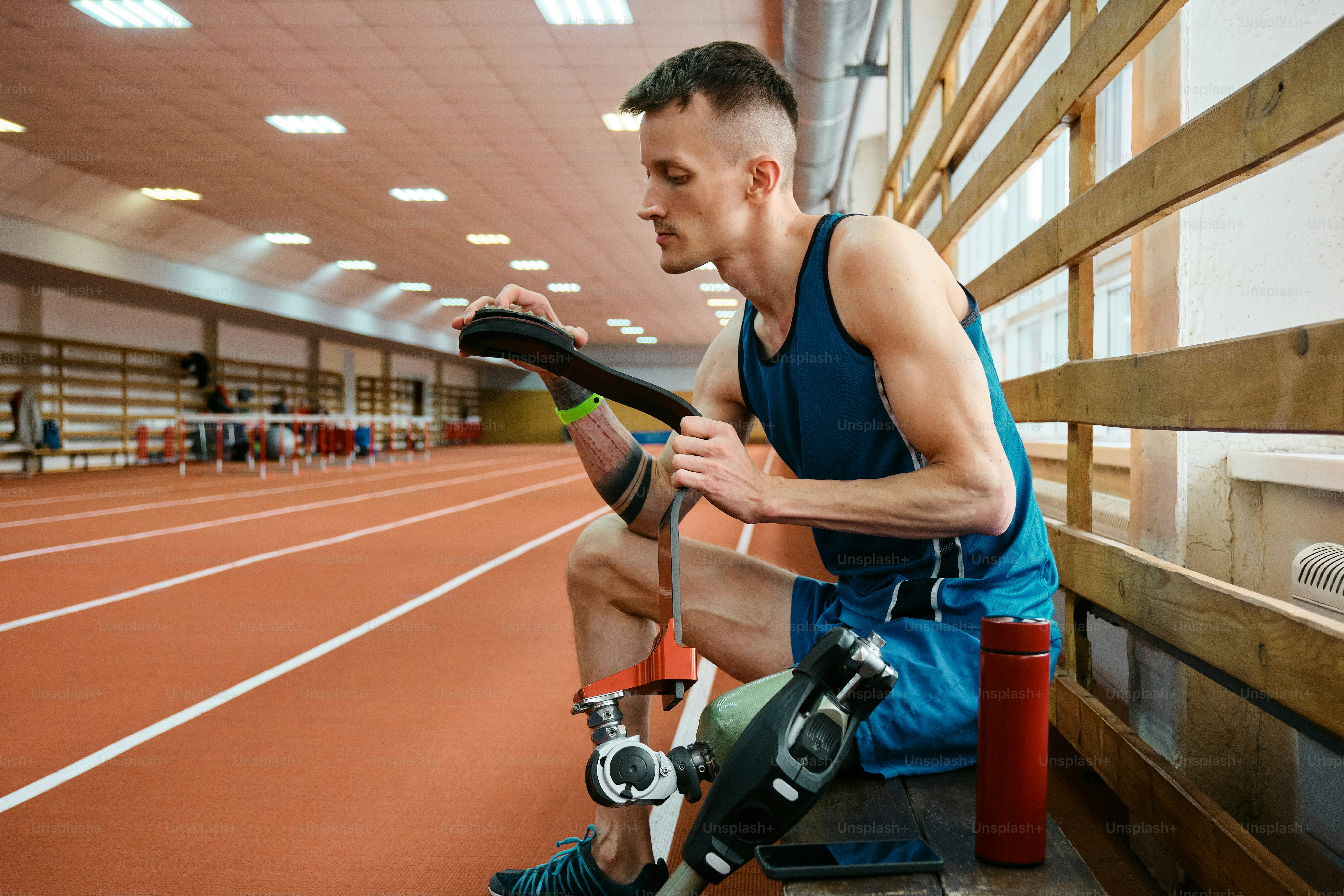 a man sitting on a bench holding a pair of knee braces
