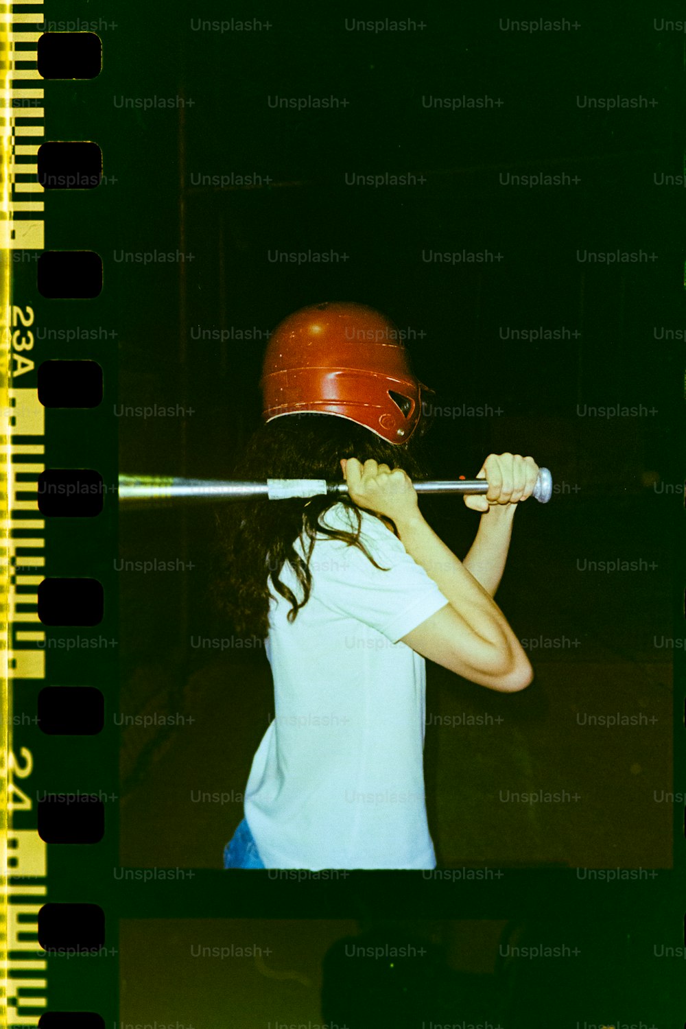 ein Mädchen mit Helm hält einen Baseballschläger in der Hand