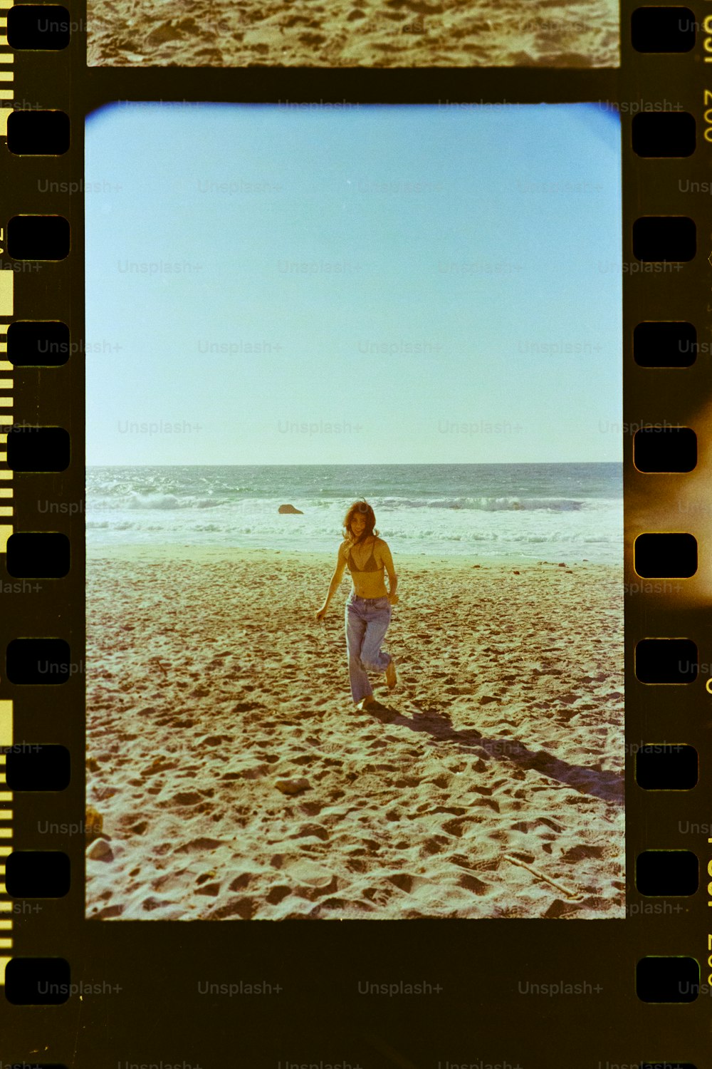 a polaroid picture of a woman walking on a beach