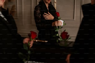 eine Frau in einem schwarzen Kleid mit einer Rose in der Hand