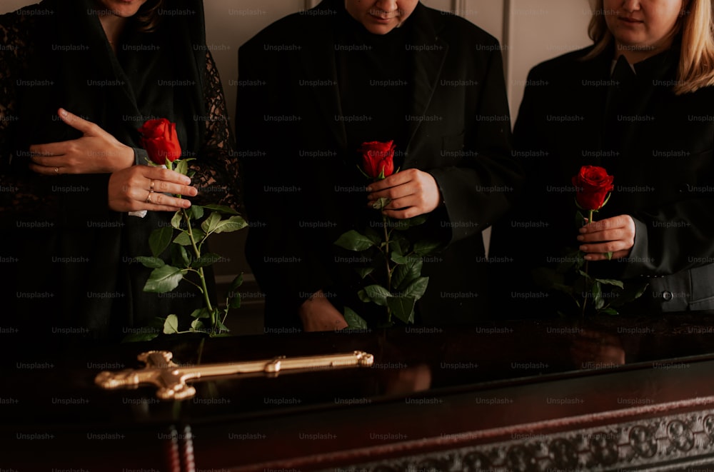 three people standing next to each other holding roses