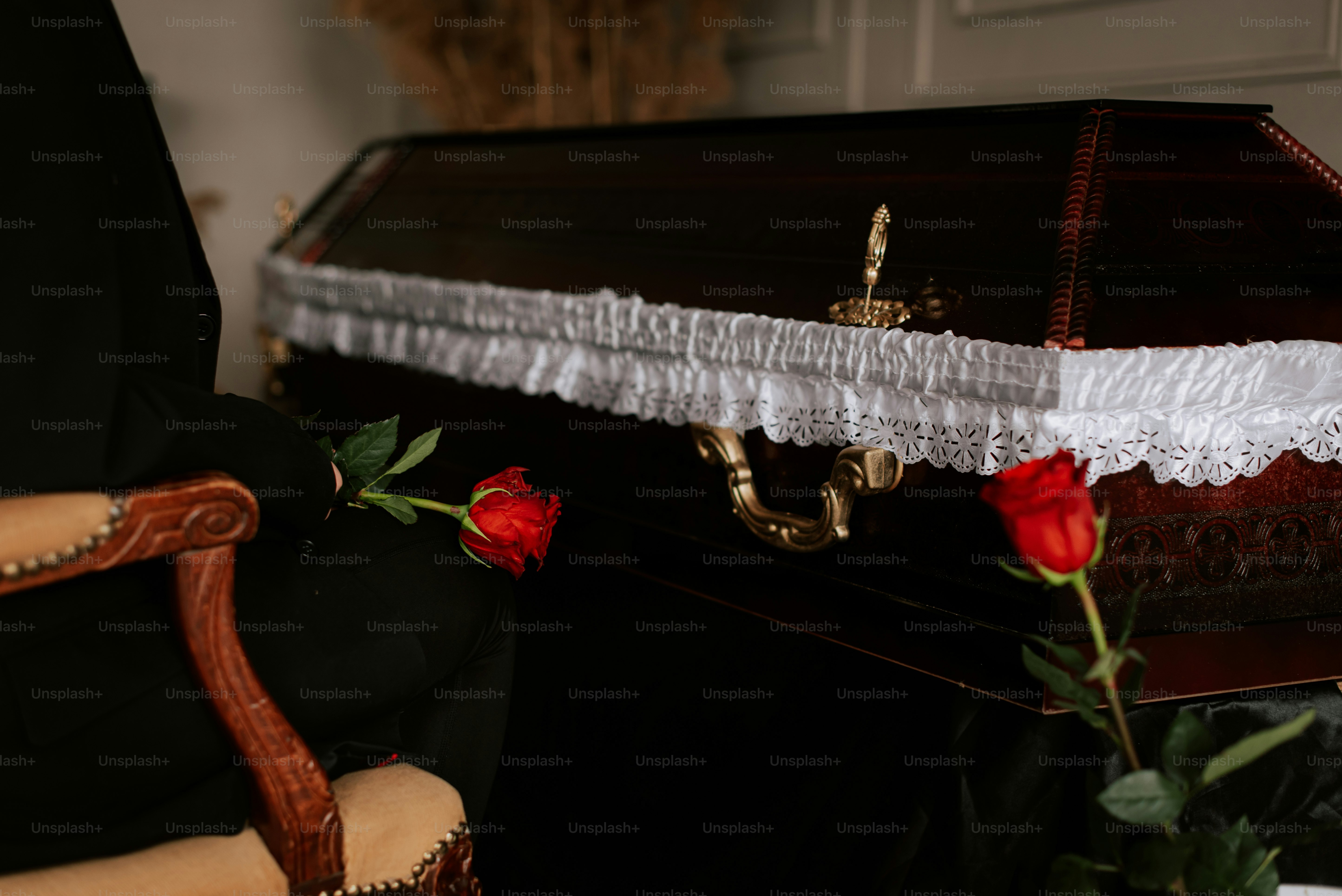 a rose sits on a chair next to a casket