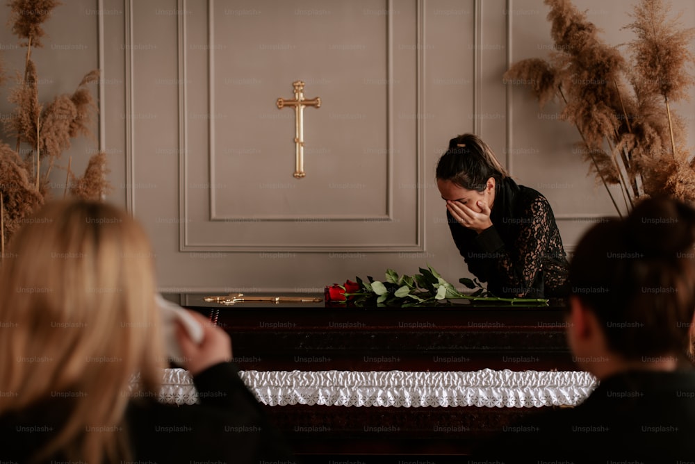 a woman sitting at a table in front of a cross