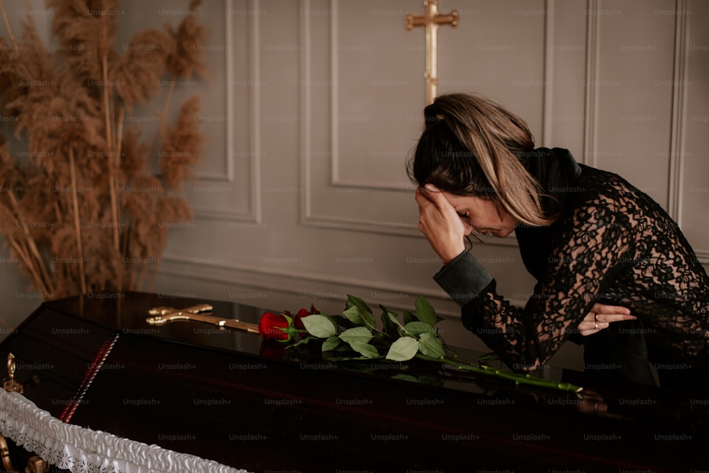 a woman kneeling down next to a casket