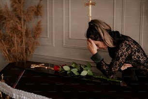 a woman kneeling down next to a casket