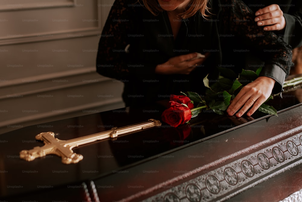 Una mujer colocando una rosa en un ataúd