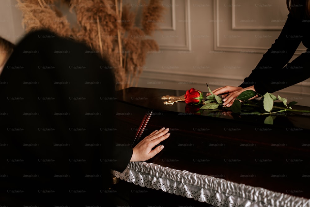 a woman is placing a rose on a table