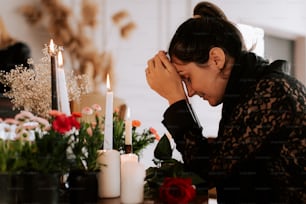 a woman sitting at a table with candles and flowers