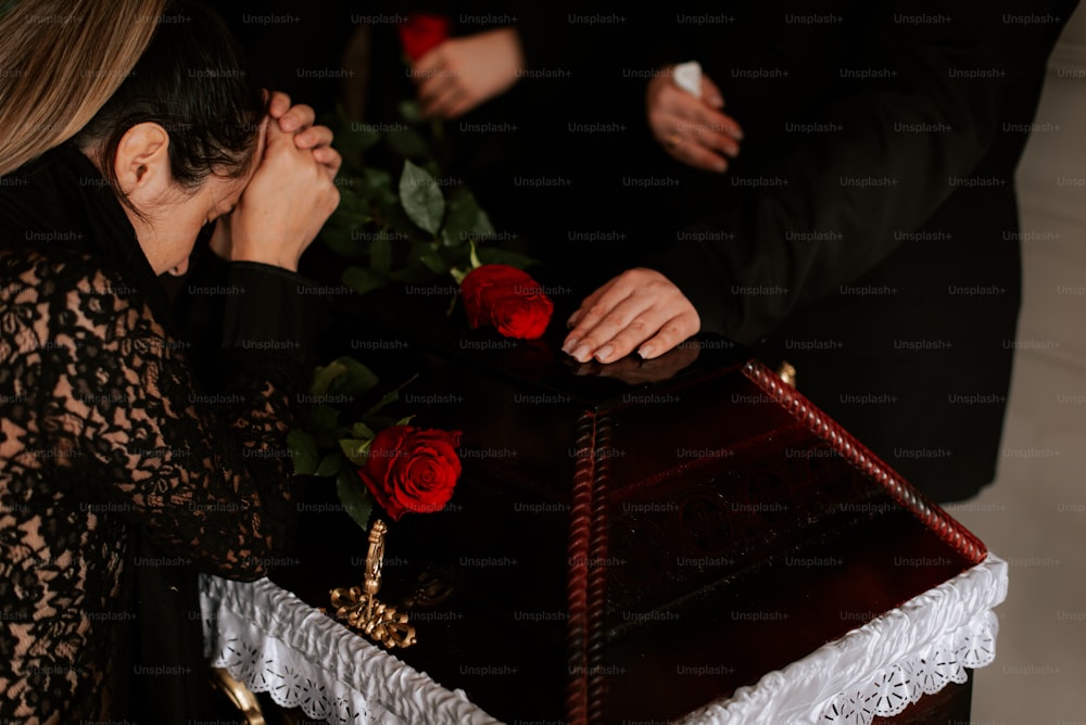 a woman sitting in front of a casket with roses on it