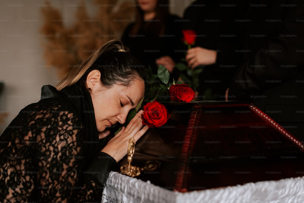 a woman placing a red rose on top of a table