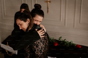 two women hugging each other in front of a cross