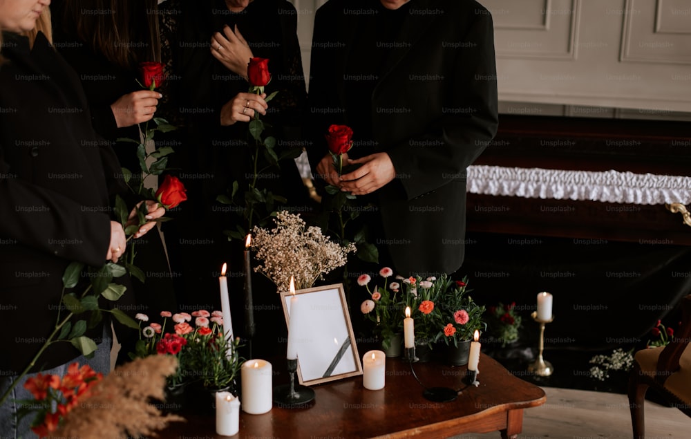 un groupe de personnes debout autour d’une table avec des fleurs