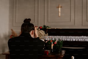 a woman sitting at a table in front of a cross