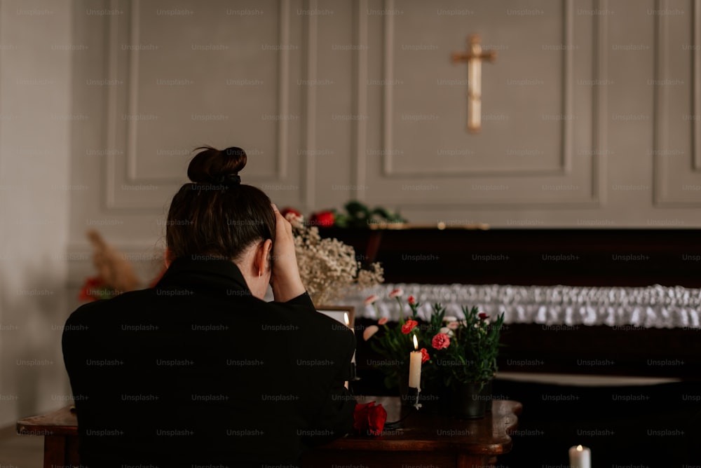 a woman sitting at a table in front of a cross