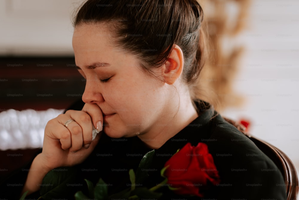 a woman sitting down with a rose in her hand