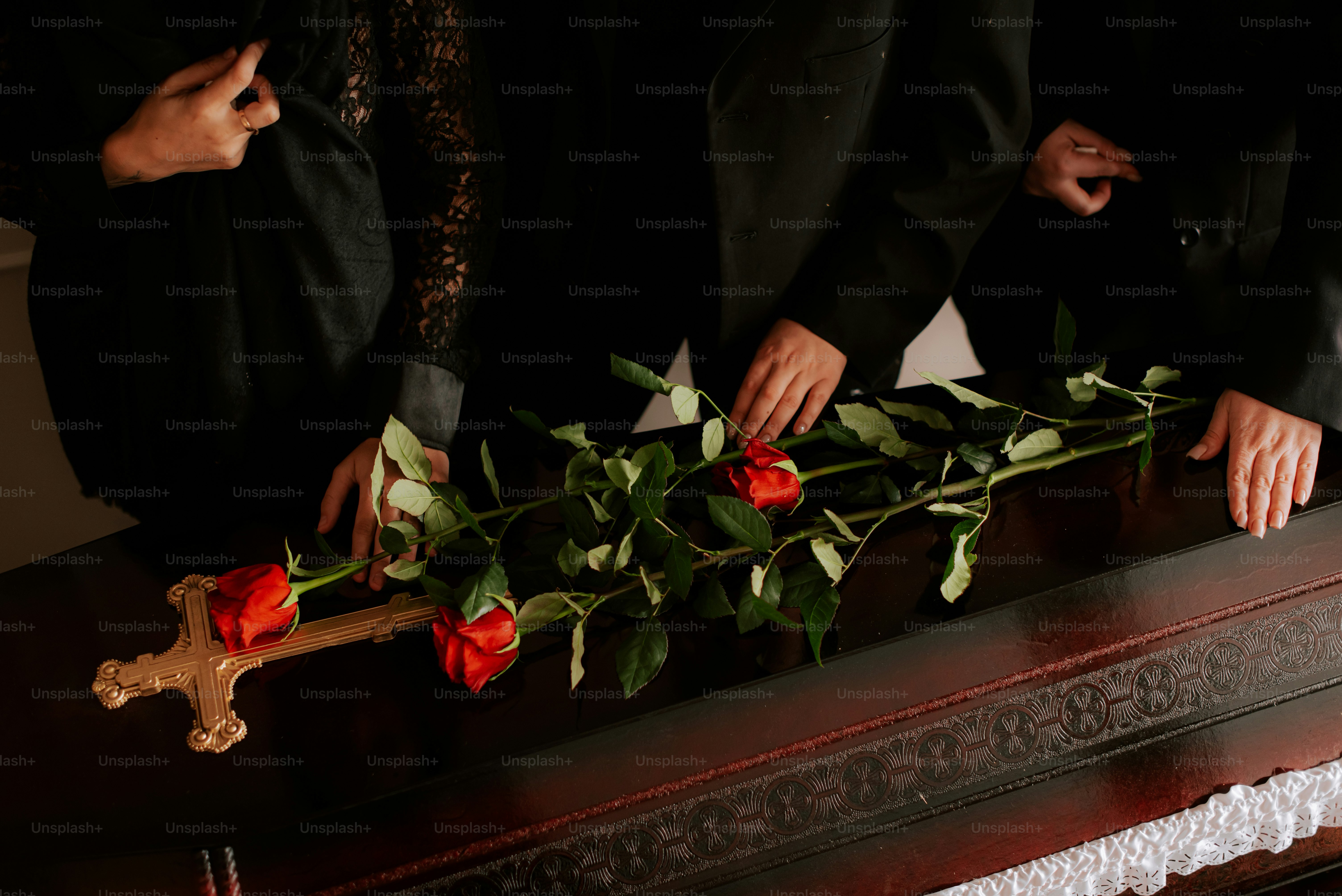 a group of people placing roses on a casket