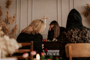 two women sitting at a table in front of a cross
