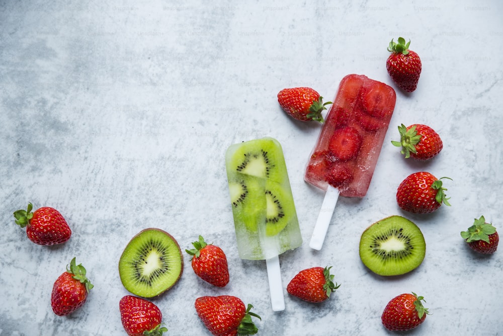 a popsicle with kiwi and strawberries on a table