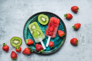 um prato de frutas em uma mesa com morangos e kiwi