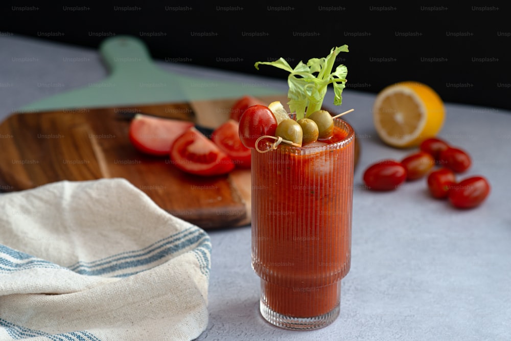 a bloody drink garnished with olives and tomatoes