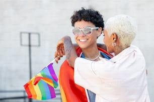 una mujer con camisa blanca y una mujer con una bandera arcoíris