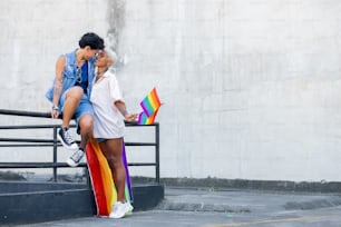a man and a woman sitting on a rainbow colored skateboard