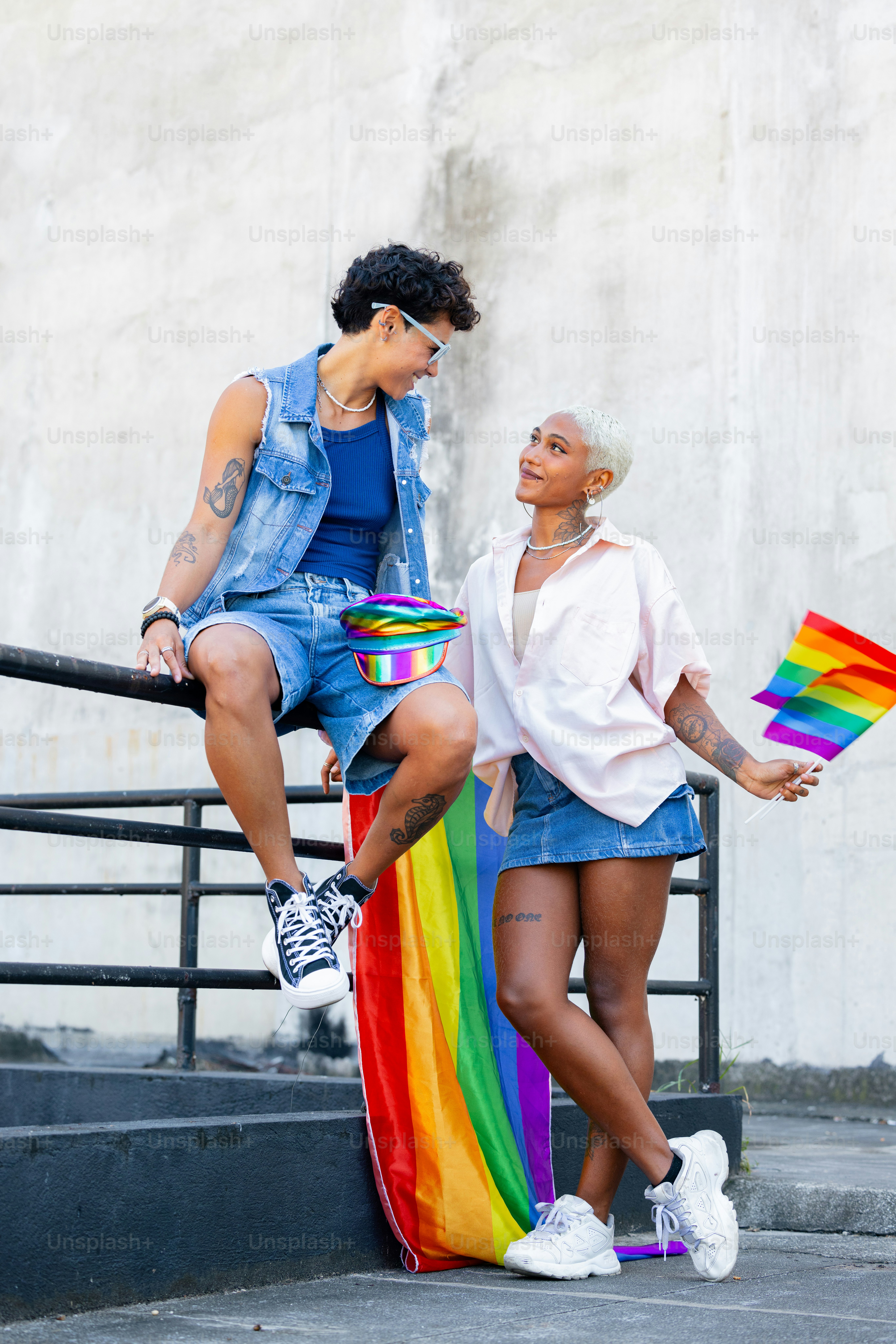 a couple of women sitting on top of a rainbow colored skateboard