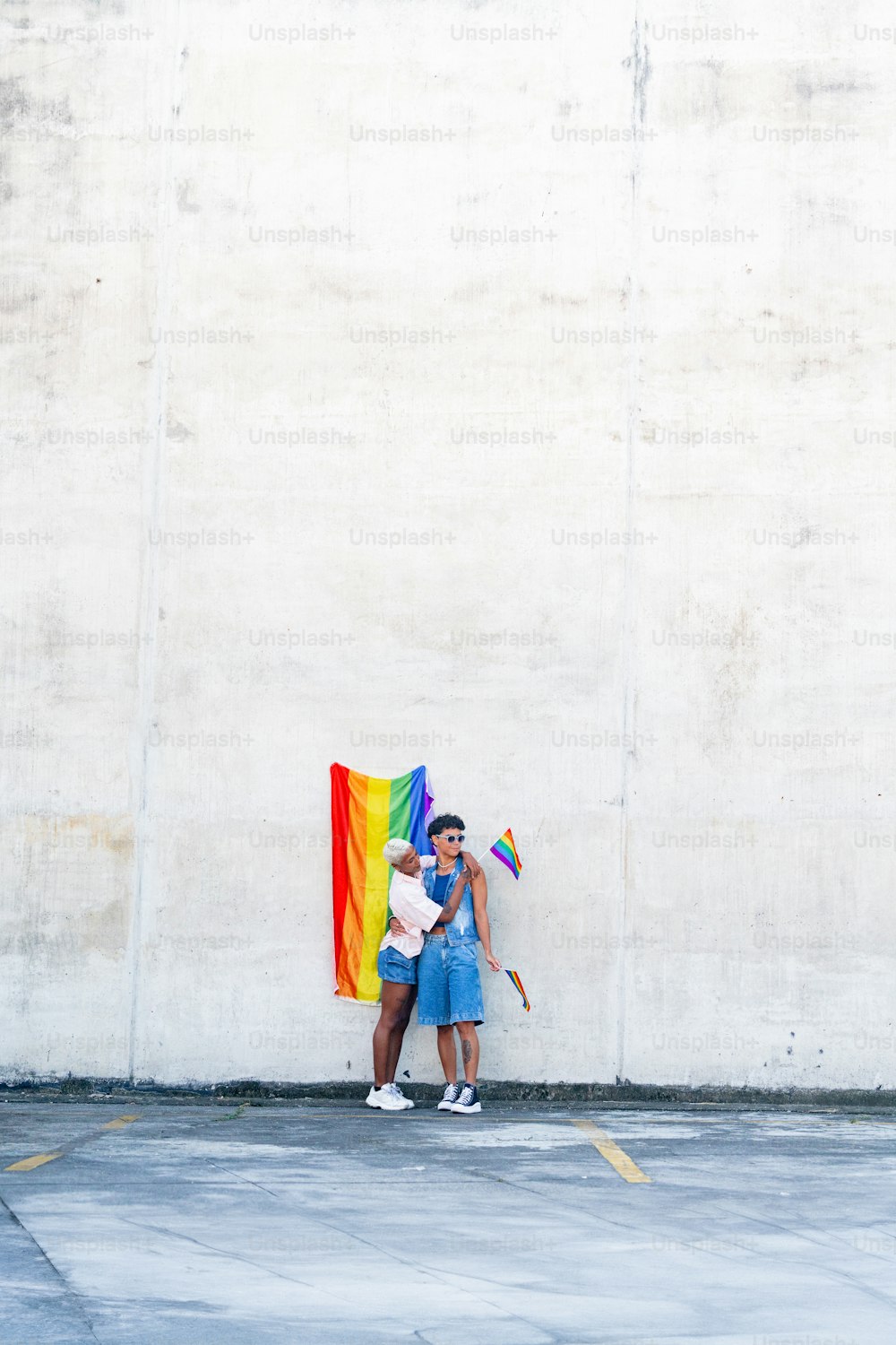 a man and a woman standing next to each other holding a rainbow flag