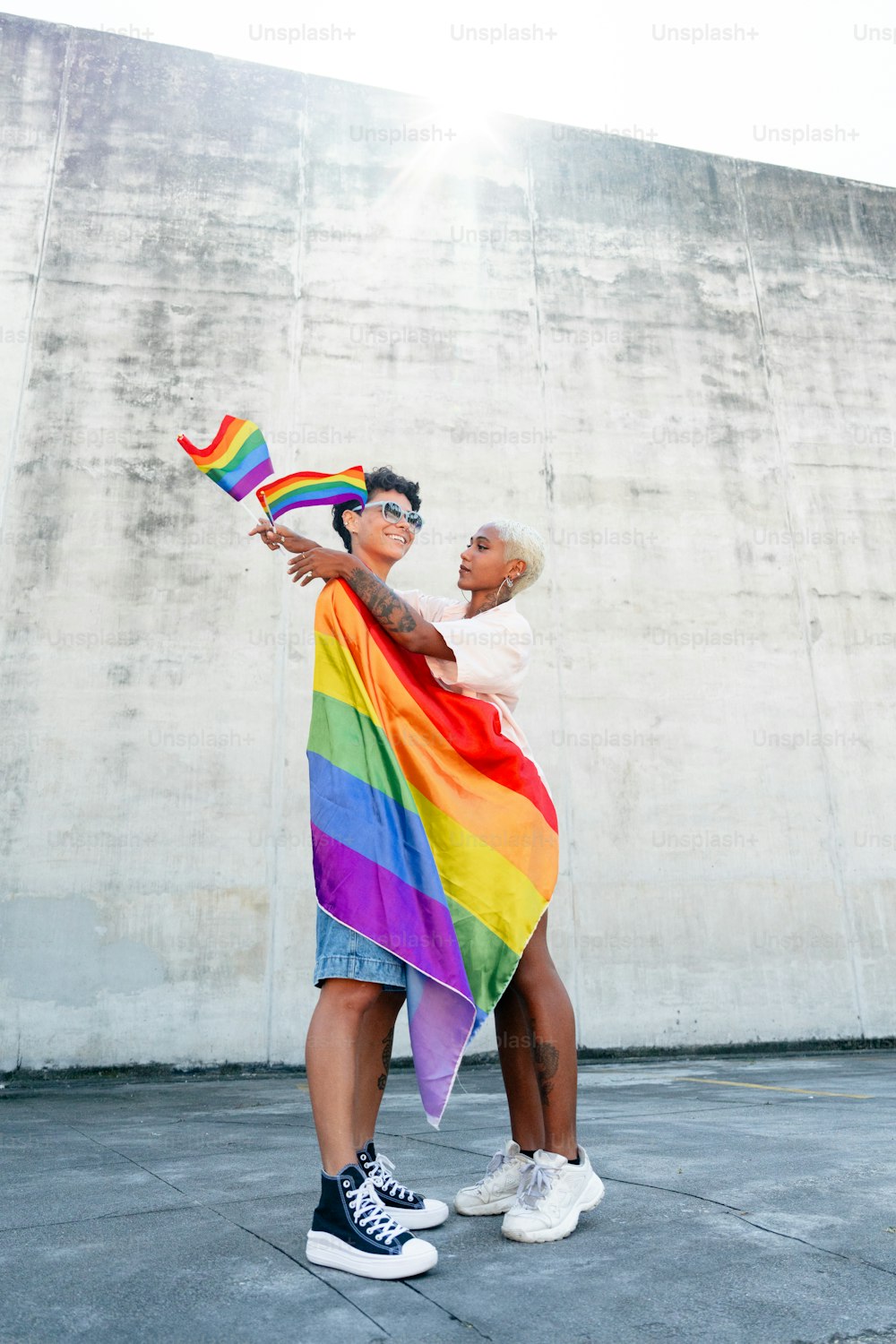 un paio di persone che tengono in mano una bandiera arcobaleno