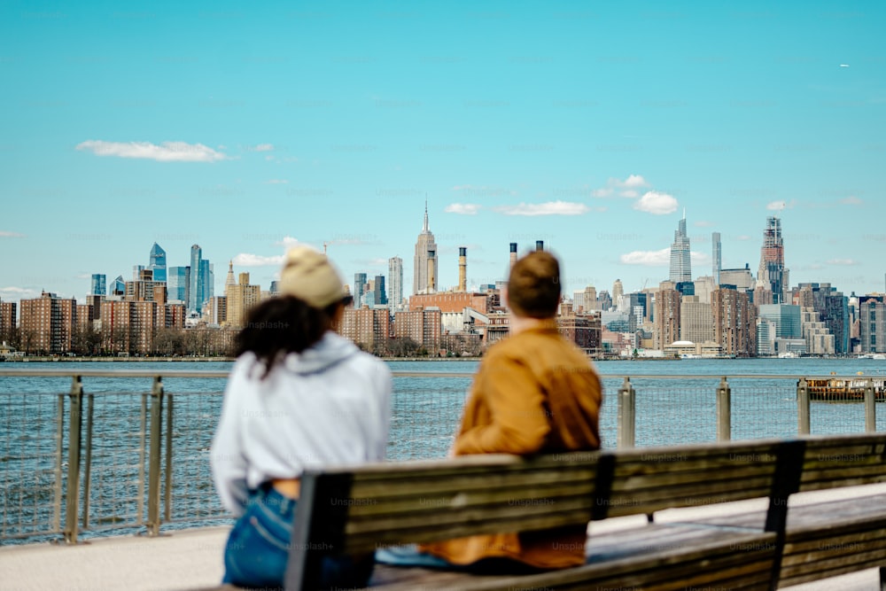 a man and a woman sitting on a bench looking at the city