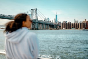 a woman looking out over the water at a bridge