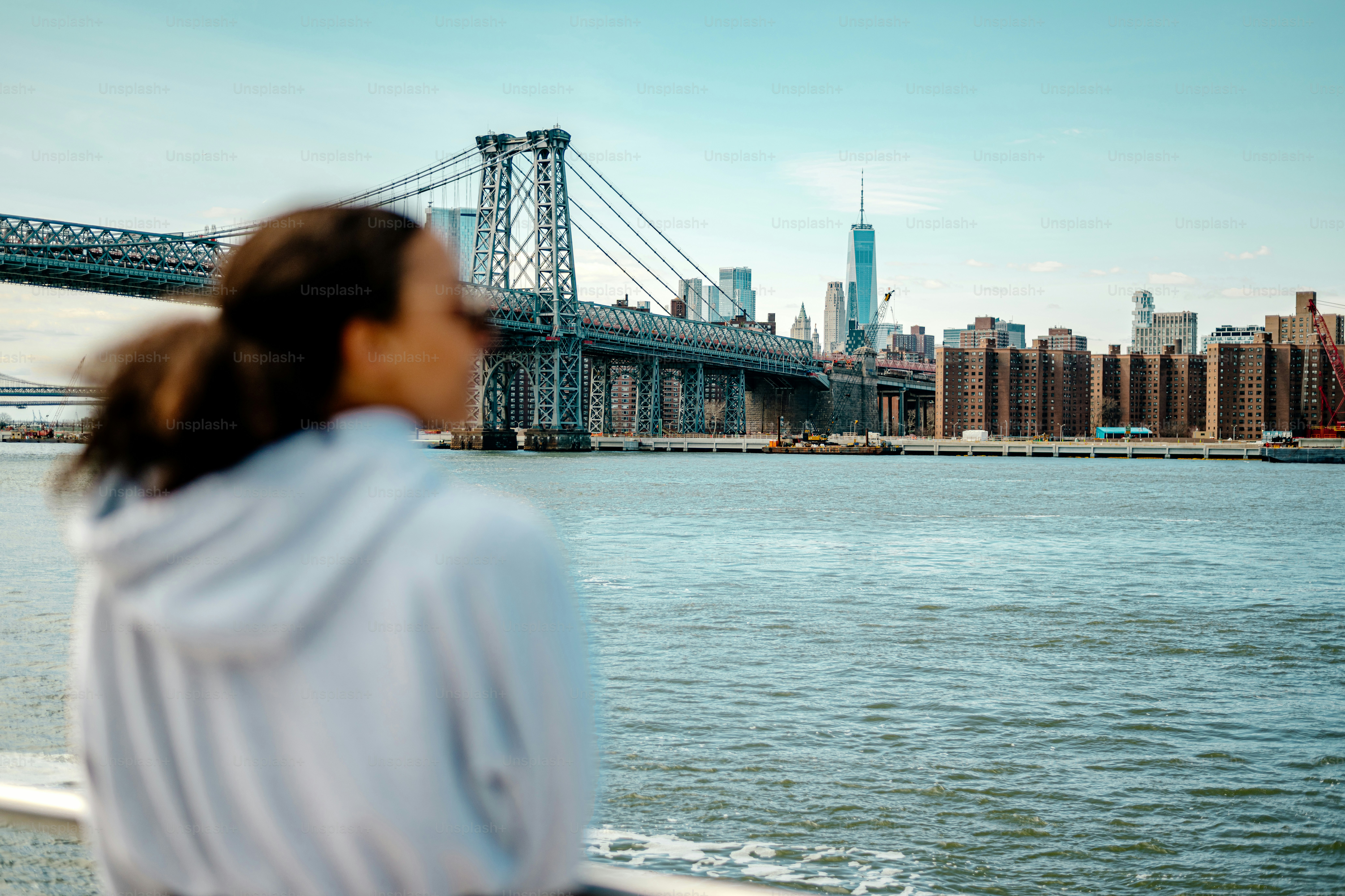 a woman looking out over the water at a bridge