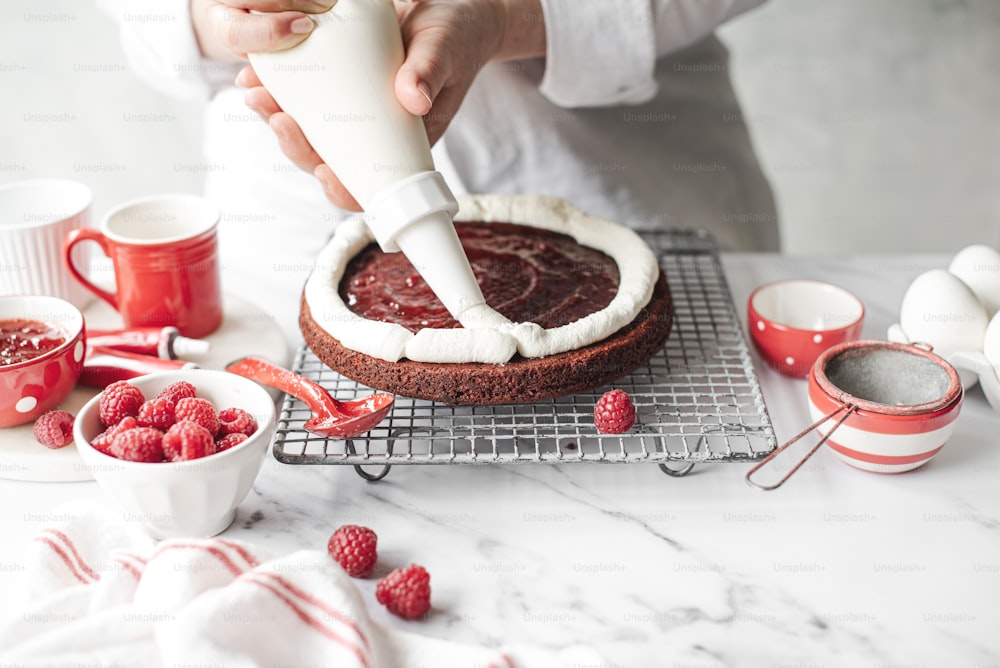 a person is decorating a cake with raspberries