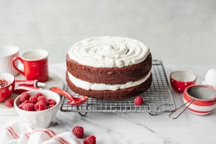 a cake with white frosting and raspberries on a cooling rack